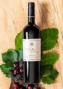 Nice bottle of Zinfandel laid atop an oak plank, with oak leaves and fruit accenting the photo. THUMBNAIL